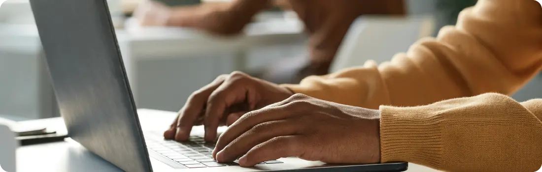 Person using a laptop, representing Windows 11's faster processing and optimized app management for improved performance.