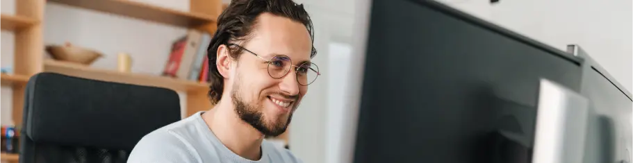 Smiling man working on a computer showcasing Power Platform solutions by ExigoTech in Singapore