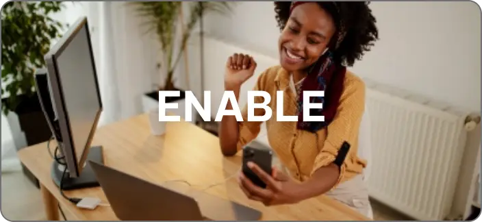 Smiling woman working on a laptop and smartphone in a home office, representing business enablement. The word 'ENABLE' is overlaid on the image.