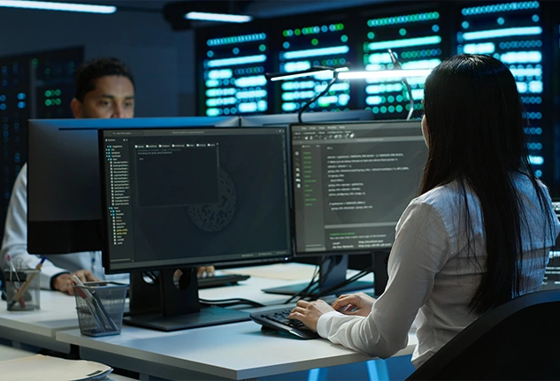 Professional using multiple computer screens to monitor and manage secure systems, representing multi-factor authentication and cybersecurity operations.